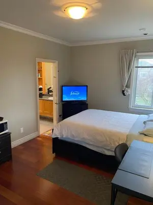 a bedroom with a bed and a flat screen tv at A cozy independent entrance bedroom with a private washroom close to YVR Richmond in Richmond