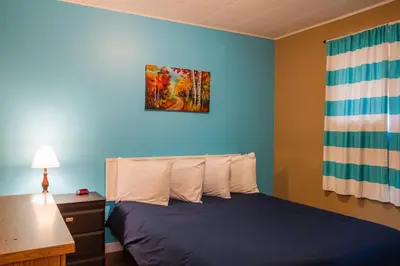 a bedroom with a bed with a desk and a painting on the wall at Lakeview Motel in Christina Lake