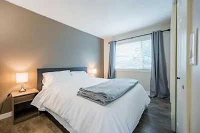a bedroom with a white bed and a window at Cozy 5BD House in North Mission Crawford in Kelowna