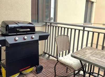 a grill on a balcony with a table and a chair at Roomy Top Floor at Stampede w Free Parking and AC in Calgary