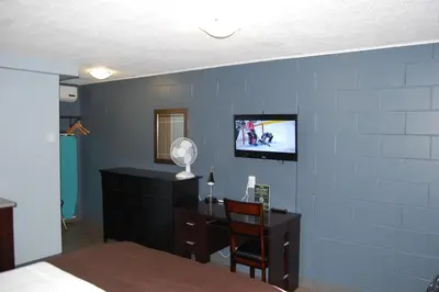 a bedroom with a desk and a tv on a blue wall at Rest Inn in Terrace