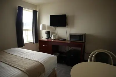 a hotel room with a bed and a desk with a television at Destination Family Hotel in Whitehorse