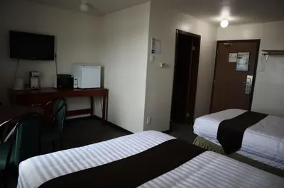 a hotel room with two beds and a desk at Destination Family Hotel in Whitehorse