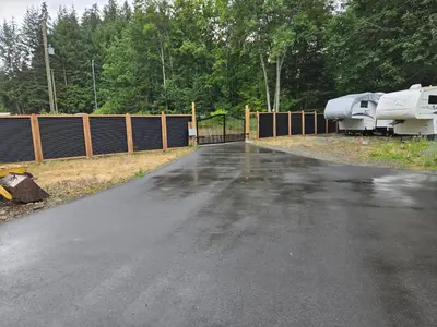 a driveway with a fence and a boat on it at Comfortable RV in a farm in Nanoose Bay