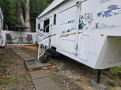 an rv parked in a yard with a table and chairs at Comfortable RV in a farm in Nanoose Bay