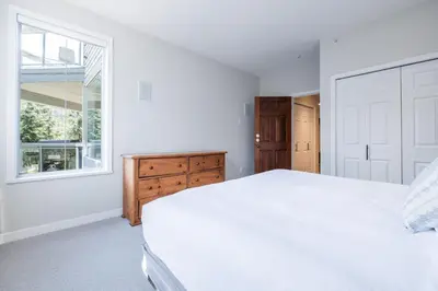 a white bedroom with a large bed and a window at Lynx by Outpost Whistler in Whistler