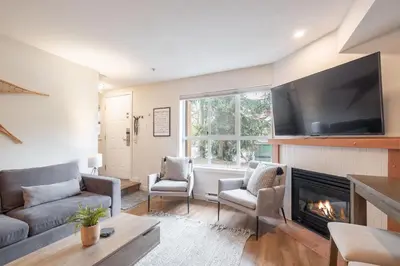 a living room with a fireplace and a flat screen tv at Glacier's Reach by Outpost Whistler in Whistler