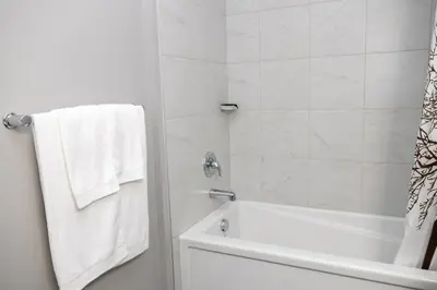 a white bathroom with a tub and a shower with white towels at The Jade Place in Airdrie