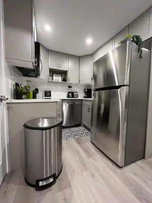a kitchen with a stainless steel refrigerator and a trash can at Private Chic Modern Suite with Kitchen near Spruce Meadows and LRT in Calgary
