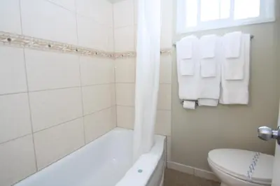 a bathroom with a tub and a toilet and towels at Harrison Spa Motel in Harrison Hot Springs