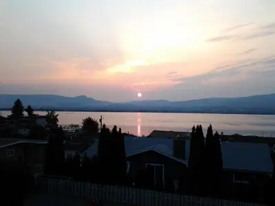 a sunset over the water in a city at Casa Loma BnB in West Kelowna