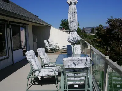 a table with chairs and an umbrella on a balcony at Casa Loma BnB in West Kelowna