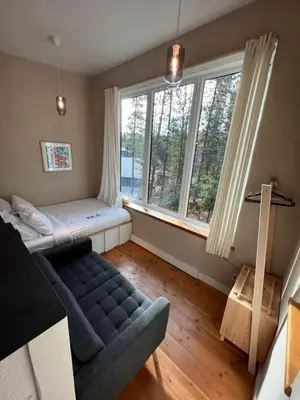 a living room with a couch and two windows at Black Spruce - Orange Door in Whitehorse