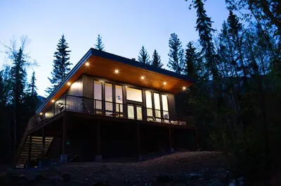 a house in the woods at night with lights at Luxury Private Cabin In The Rockies in Golden