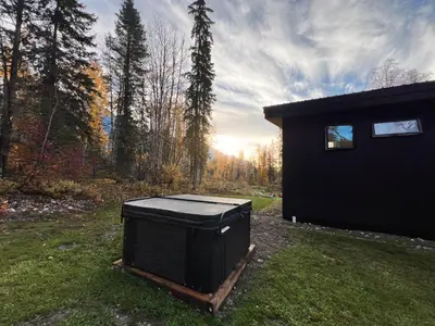 a trash can sitting in the grass next to a house at Luxury Private Cabin In The Rockies in Golden