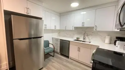 a kitchen with white cabinets and a stainless steel refrigerator at Unit #204 Cozy Mountain View 2BR in Canmore Downtown in Canmore