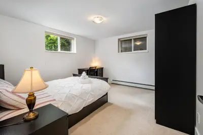 a bedroom with a bed and a lamp on a desk at Gorgeous 4 Bedroom Garden Level Suite at Vancouver West & UBC in Vancouver