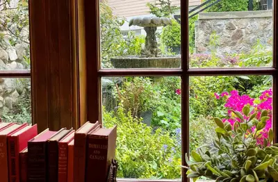 a window view of a garden with books and a fountain at The Latch Inn in Sidney