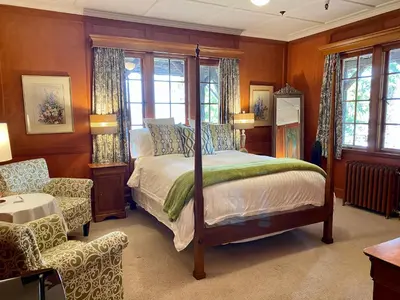 a bedroom with a bed and a chair and windows at The Latch Inn in Sidney