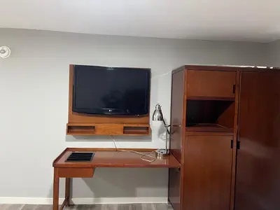 a flat screen tv sitting on a wall with a desk at Bethel hotel Elk Point in Elk Point
