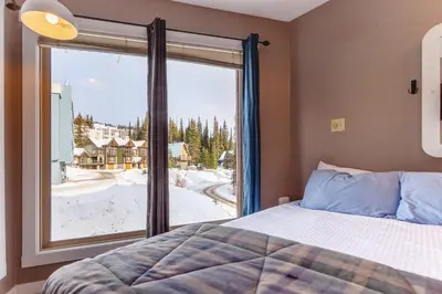 a bedroom with a bed and a large window at The Ridge Ski-In Ski-Out Condo with Free Parking in Big White