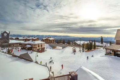 a ski resort with people skiing on a snow covered slope at The Ridge Ski-In Ski-Out Condo with Free Parking in Big White