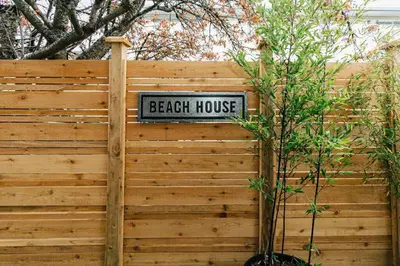 a sign that reads beach house on a wooden fence at Lovely 2 bedroom suite steps from The beach in Victoria