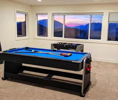 a room with a pool table in front of windows at Mountain Retreat with Views, Hot Tub, Games & AC in Chilliwack