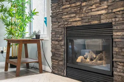 a living room with a stone fireplace with a table at R&R Relaxation Ridge, Private Hot Tub, Spacious in Radium Hot Springs