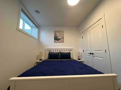 a bedroom with a blue bed and a window at 2BR Suite, Private Entry, Full Kitchen, Washer & Dryer, Free Parking, Smart TV with Netflix, High-Speed Wi-Fi, Self Check-In, Near Banff National Park in Calgary