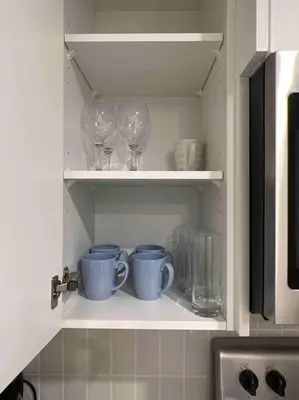 a cupboard with two cups and wine glasses at 2BR Suite, Private Entry, Full Kitchen, Washer & Dryer, Free Parking, Smart TV with Netflix, High-Speed Wi-Fi, Self Check-In, Near Banff National Park in Calgary