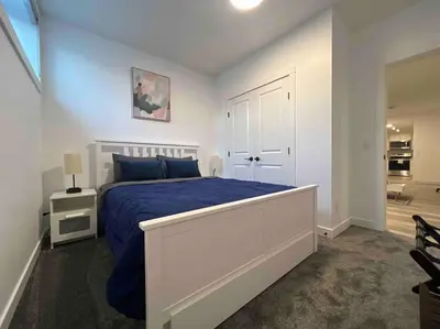 a bedroom with a bed with a blue comforter at 2BR Suite, Private Entry, Full Kitchen, Washer & Dryer, Free Parking, Smart TV with Netflix, High-Speed Wi-Fi, Self Check-In, Near Banff National Park in Calgary