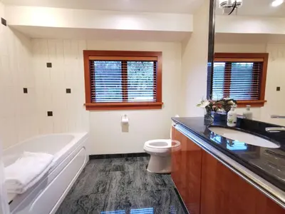 a bathroom with a tub and a toilet and a sink at Deep Cove Stunning Waterfront Whole House in North Vancouver