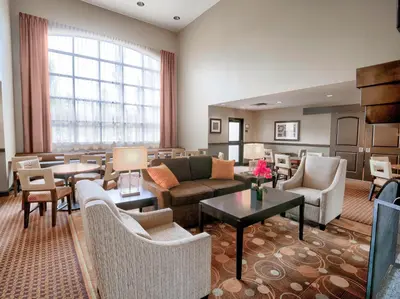 a living room with couches and tables and chairs at Staybridge Suites West Edmonton by IHG in Edmonton