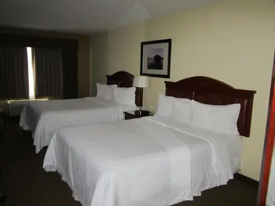 two beds in a hotel room with white sheets at Trend Mountain Hotel & Conference Centre in Tumbler Ridge