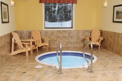 a hot tub in a room with chairs and a table at Trend Mountain Hotel & Conference Centre in Tumbler Ridge