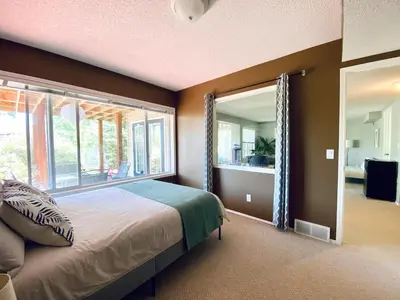 a bedroom with a bed and a large window at Private, Spacious, & Bright Home in Calgary