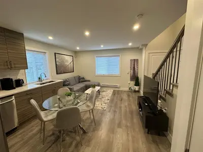 a kitchen and a living room with a table and chairs at Bright and cozy modern home in Vancouver - central to YVR-Downtown - Free Private Parking in Vancouver