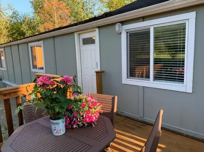 a table with flowers on a porch with a window at Cosy country mobile home on 18 acres farm sleeps 5 in Port Alberni