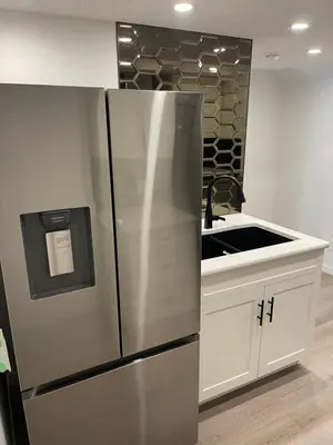 a kitchen with a stainless steel refrigerator and a sink at Grande Villa in Calgary