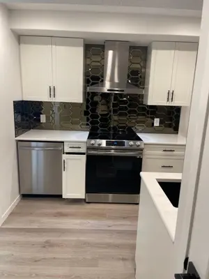 a kitchen with stainless steel appliances and white cabinets at Grande Villa in Calgary
