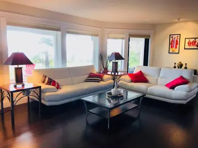 a living room with a white couch and red pillows at Saanichton Waterfront 2BR suite with superb views in Saanichton