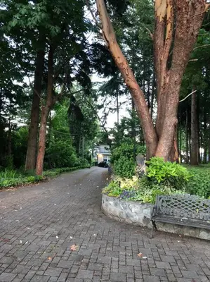 a brick road with trees and a bench in a park at Saanichton Waterfront 2BR suite with superb views in Saanichton