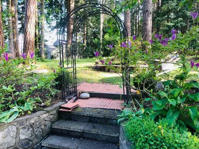 a garden with a gate and stairs with purple flowers at Saanichton Waterfront 2BR suite with superb views in Saanichton