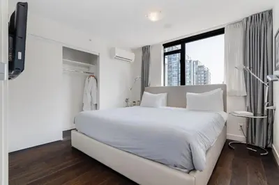 a white bedroom with a large bed and a window at Level Vancouver Yaletown Seymour in Vancouver