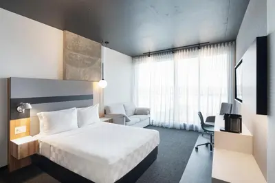 a hotel room with a white bed and a chair at Alt Hotel Calgary University District in Calgary
