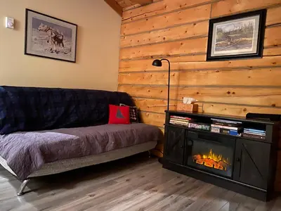 a living room with a couch and a fireplace at Oma's and Opa's Northern Lights Viewing Cabin in Whitehorse