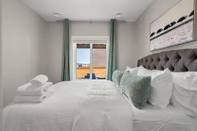 a bedroom with a large white bed with a window at Modern Basement Gem: 2 BR Retreat in Calgary