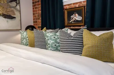 a bunch of pillows on a bed in a room at Luxe New York Style Bsmt Suite, Near DT & WEM, King Bed, WiFi in Edmonton