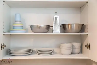 a shelf with plates and bowls in a kitchen at Luxe New York Style Bsmt Suite, Near DT & WEM, King Bed, WiFi in Edmonton